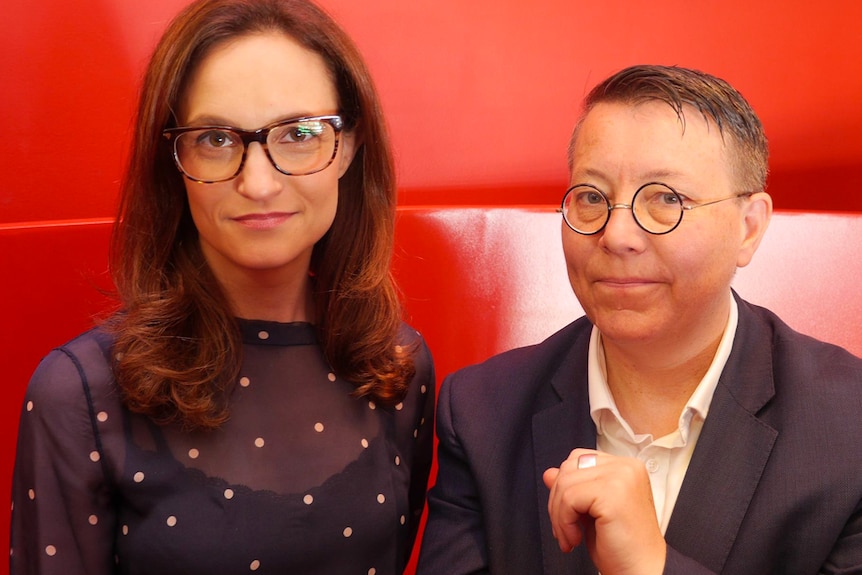 Elena Pappas (left) and Jill Prior (right) stand in front of a red backdrop.