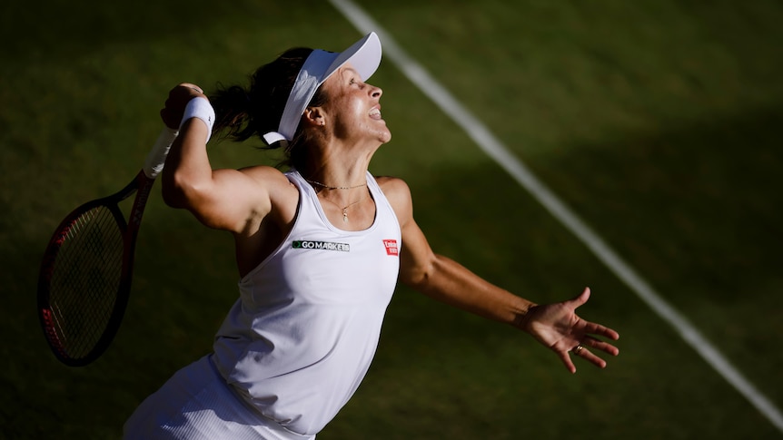 A female tennis player wearing white prepares to hit a ball