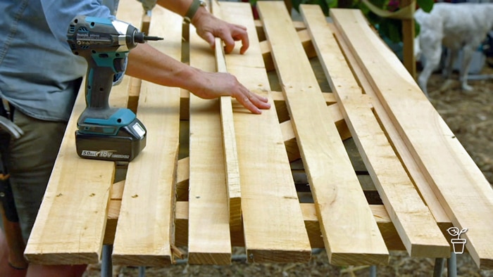 Timber slats being placed on a wooden frame with cordless drill in foreground.