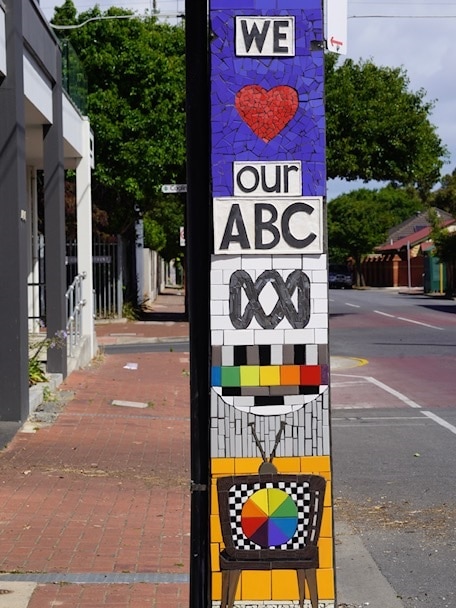 A stobie pole with a mosaic artwork saying 'we love our ABC'