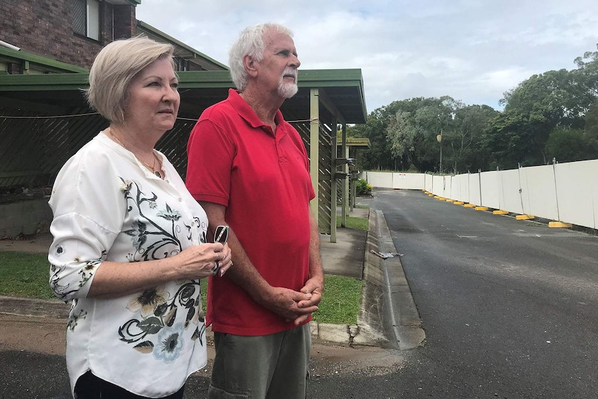 Julia and Anthony Mayfield stands outside their unit at Rochedale South, looking at temporary fencing.