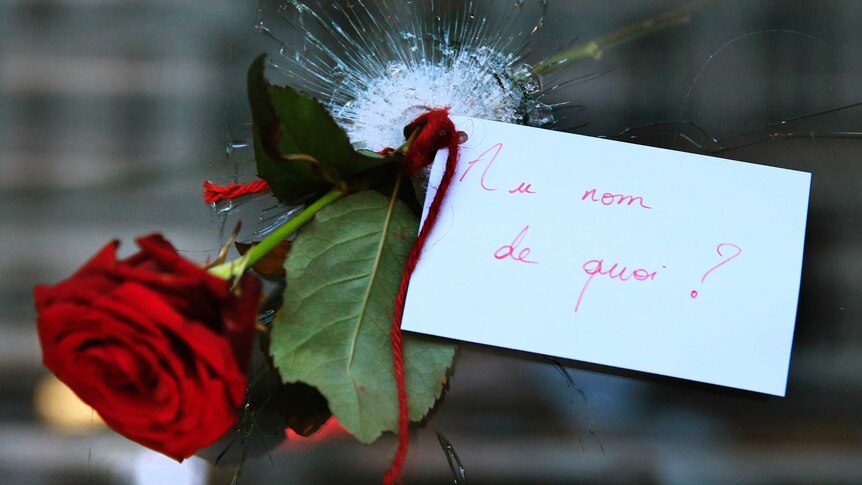 A rose placed in a bullet hole in a restaurant window the day after the Paris attacks.
