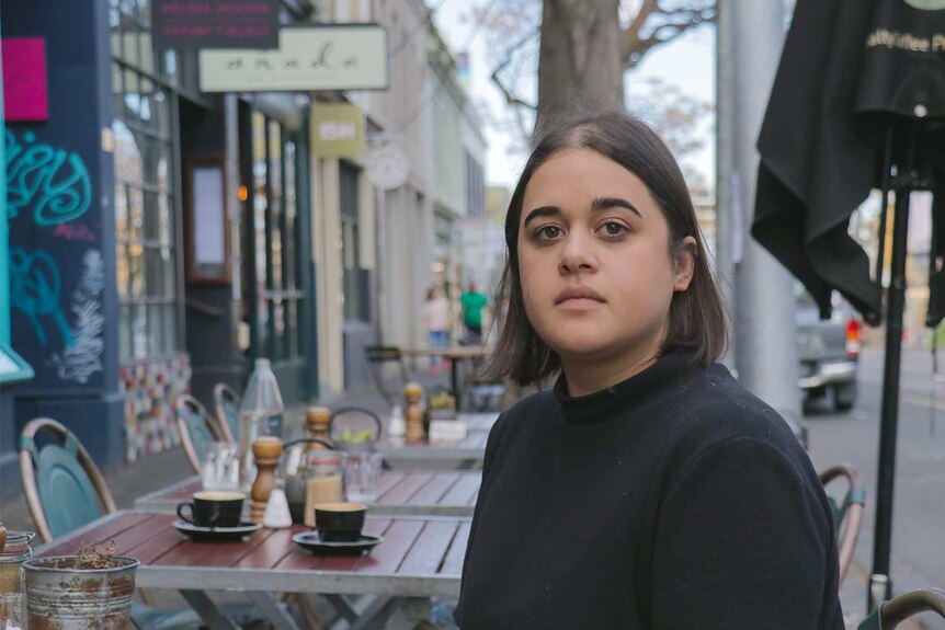 Caitlin Scaife sits down with a coffee at a cafe in Collingwood.