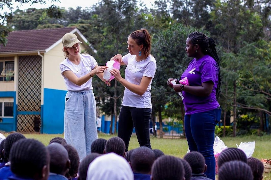 Two women showing a pad to a class with another woman standing up