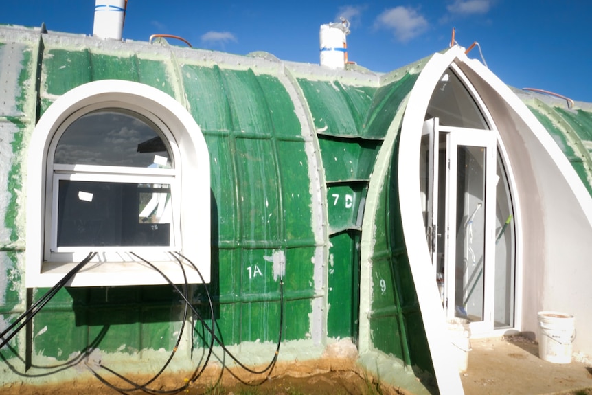 Exterior detail of modular house with cables hanging through window and drainage issues