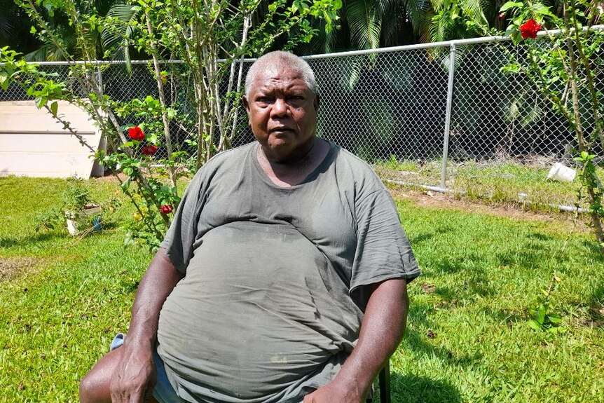 An Indigenous man sits in his backyard.