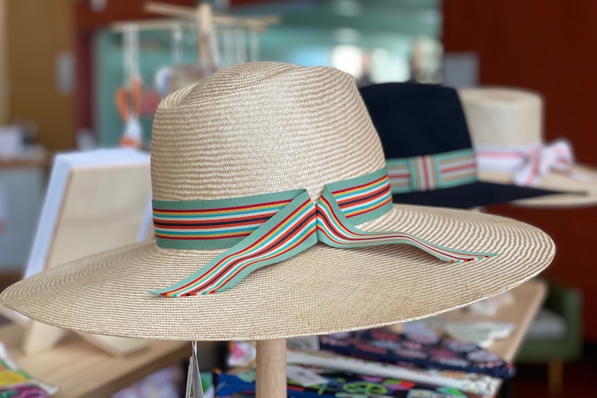 A straw hat with a multi colour ribbon wrapped around it