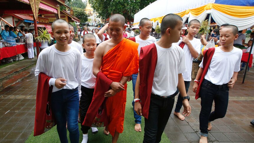 The boys walk with their former coach dressed in an orange monks' robe.