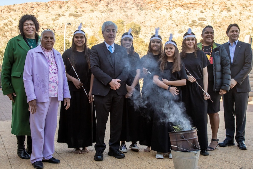 A group of people standing around a fire for an Aboriginal smoking ceremony