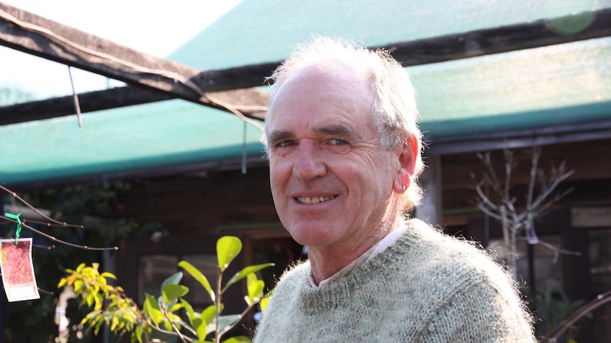 Portrait of a man from mid-torso up, standing in a garden nursery.