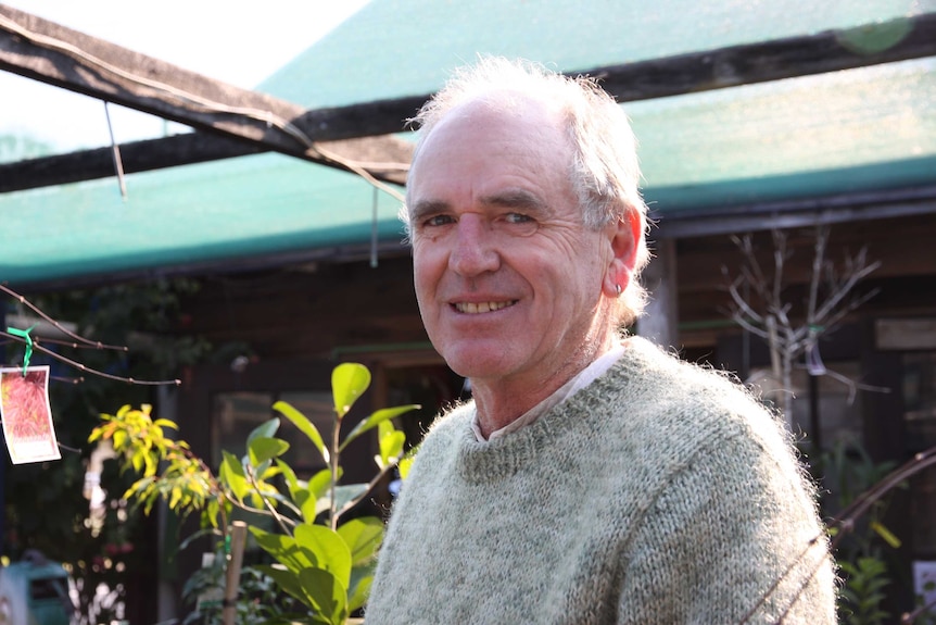 Portrait of a man from mid-torso up, standing in a garden nursery.