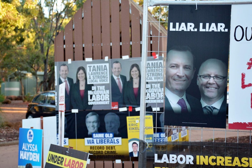 Campaign posters cover fences outside a polling booth in Darling Range.