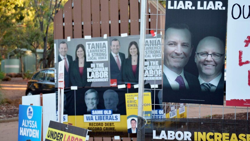 Campaign posters cover fences outside a polling booth in Darling Range.