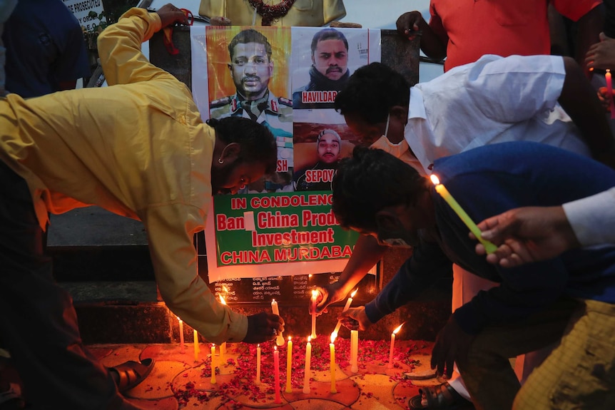 Indians light candles in front of pictures of men that were killed.