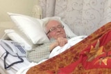 elderly man sleeping in bed with a phone next to him