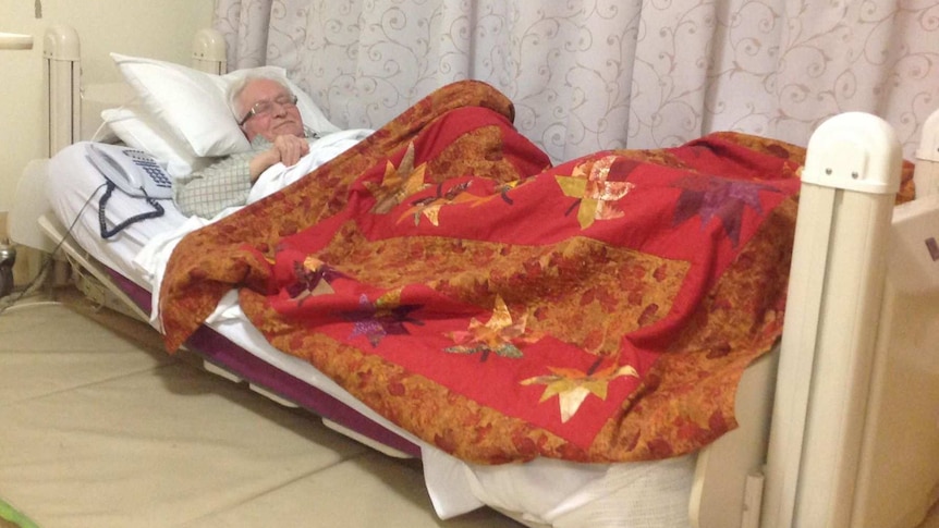 elderly man sleeping in bed with a phone next to him