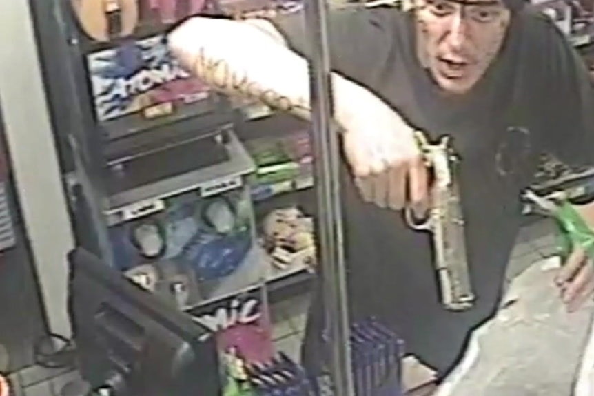 CCTV image of Samuel Grant covered in fake tattoos drawn on with a black market and a replica handgun.