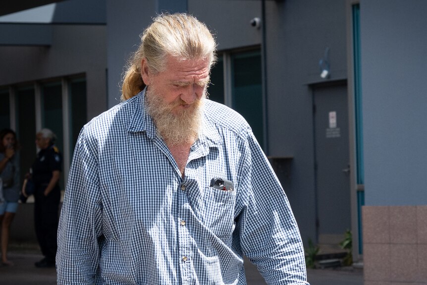 A man with beard and long hair walks across the courthouse courtyard