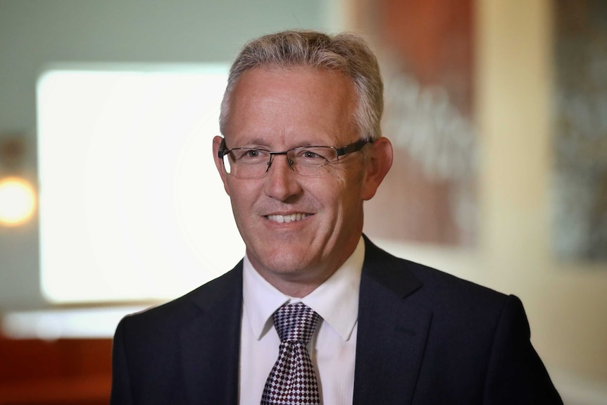 ACT Labor Senator David Smith in the Mural Hall of Parliament House. He's smiling and wearing glasses.