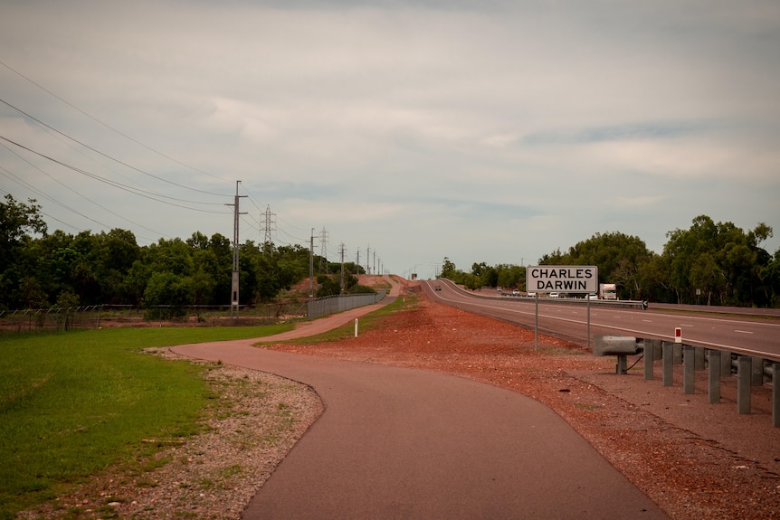 A treeless cycle path beside a highway with a location sign saying 'Charles Darwin'.