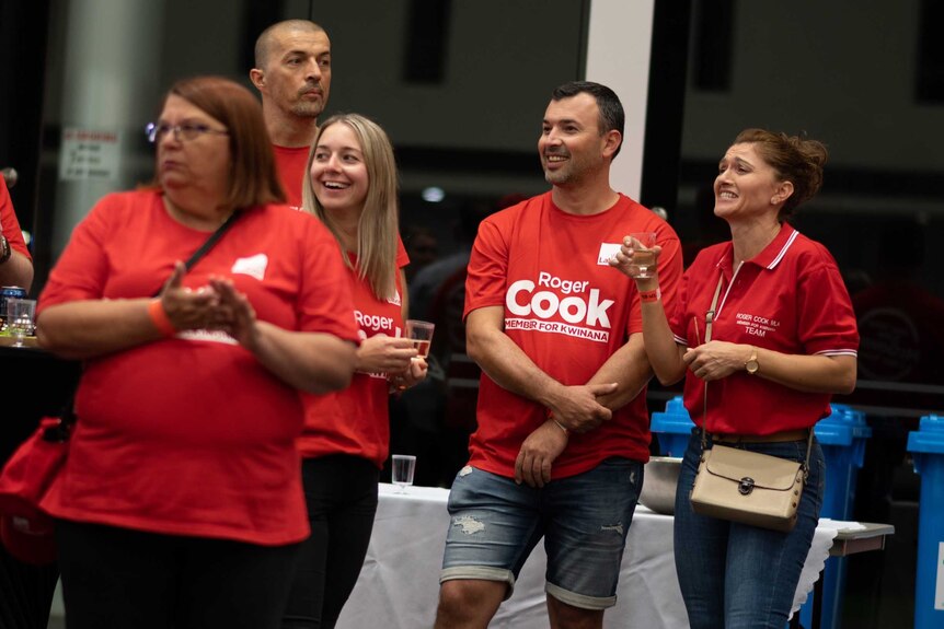 Labor supporters in red shirts smiling and drinking