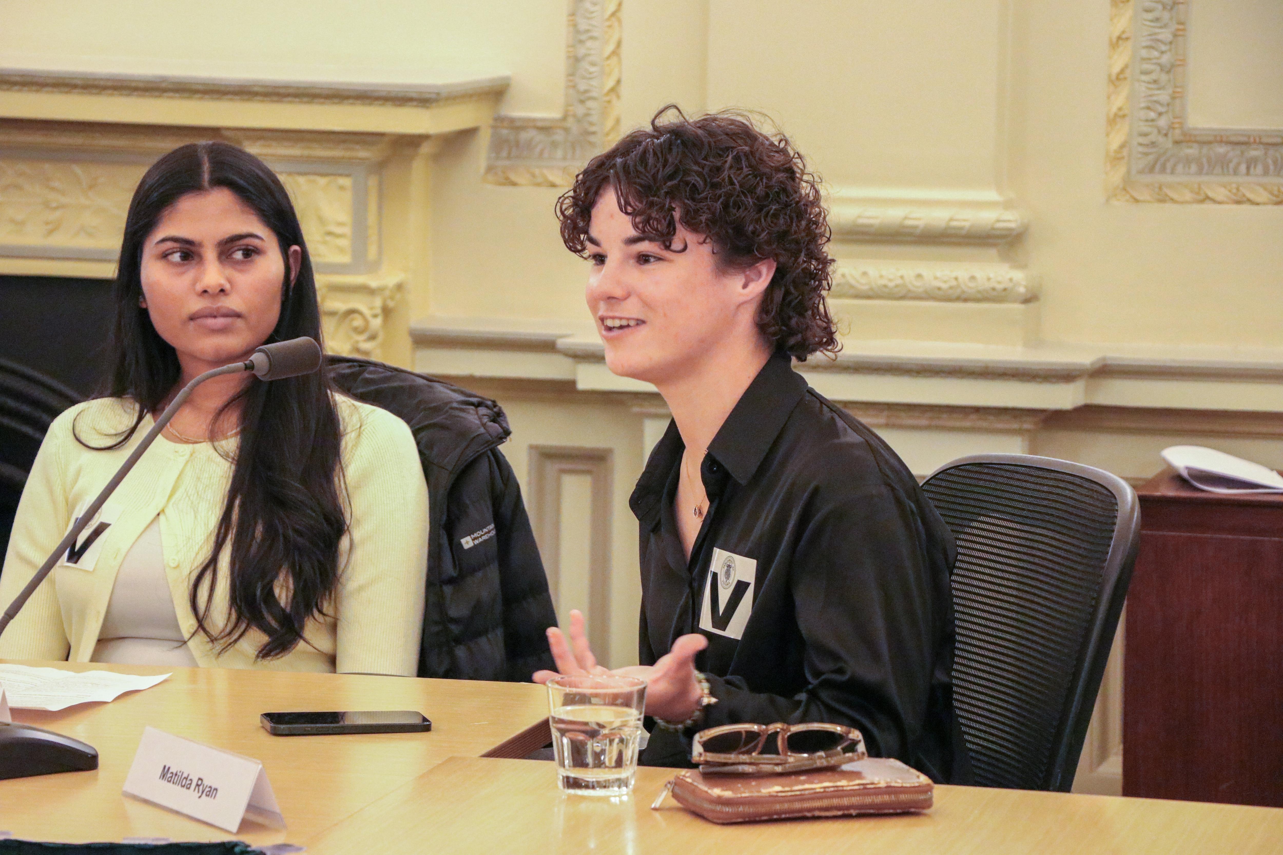 Mujeres con camisa negra hablan por un micrófono en el Parlamento victoriano. 