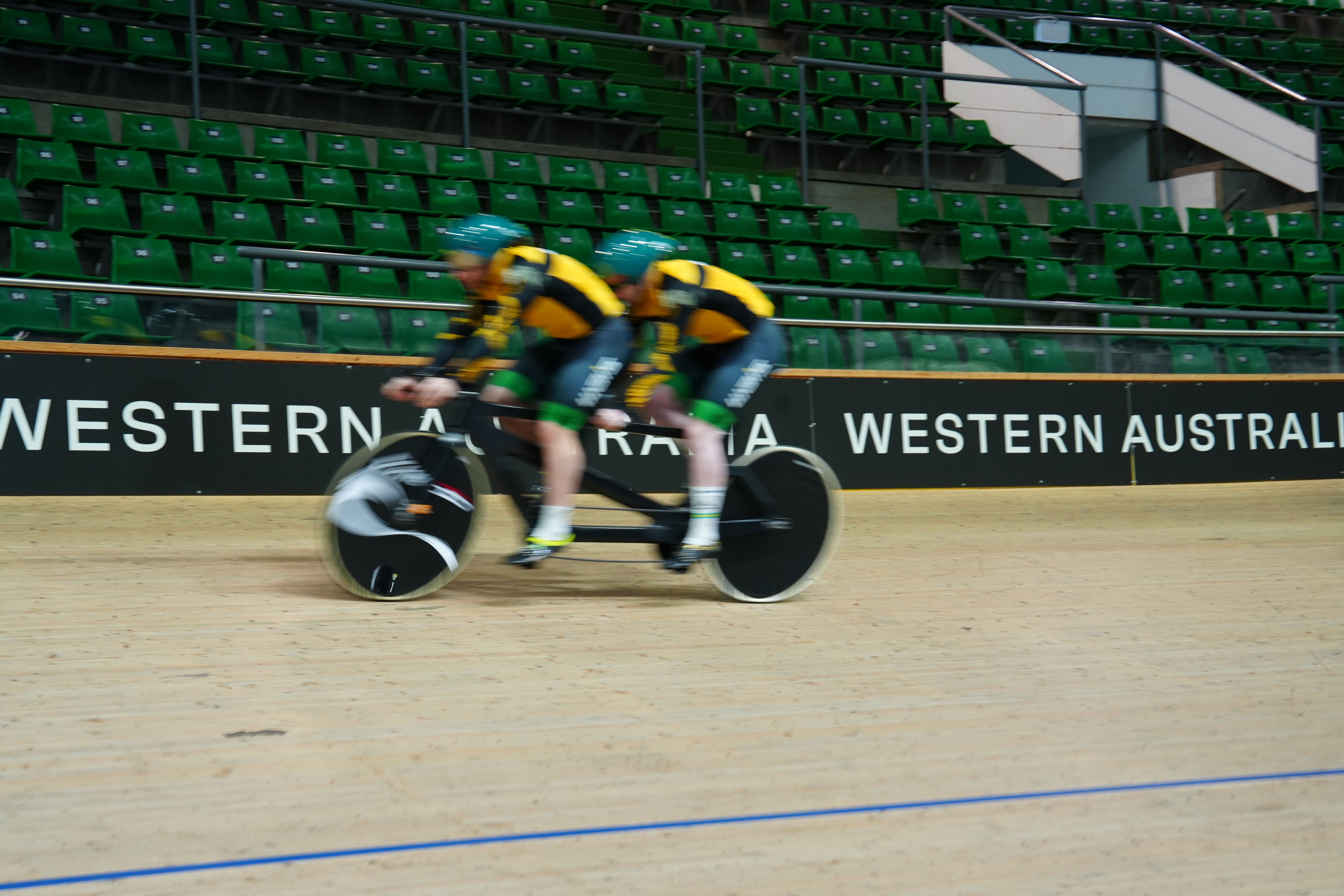 Cyclists Luke Zaccaria (front) and Kane Perris ride a tandem bike at a velodrome. 