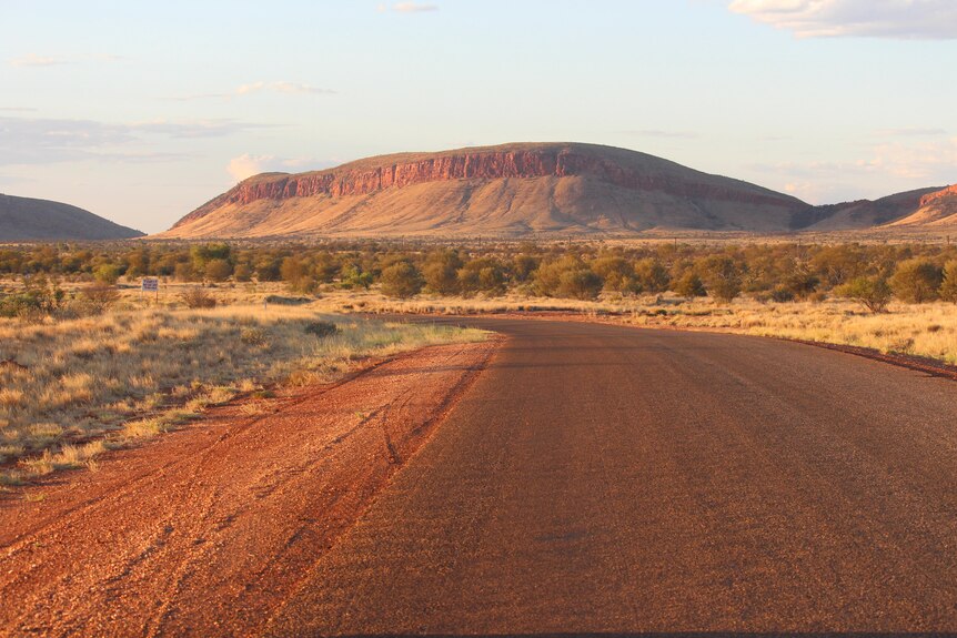 A road leading towards a high red escarpment