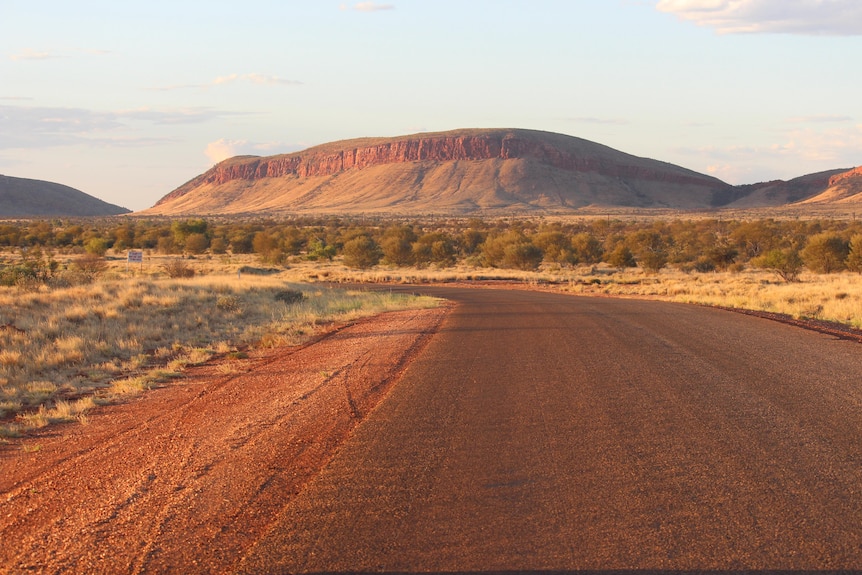 A road leading towards a high red escarpment