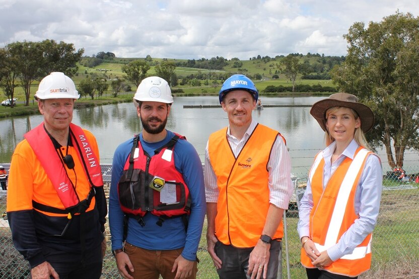 Three men and one woman in front of solar floating farm