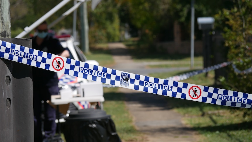 Police tape across footpath on Brisbane street