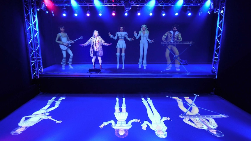 A fan sings with giant holograms of ABBA members.