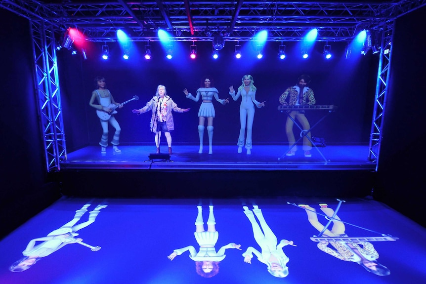 A fan sings with giant holograms of ABBA members.