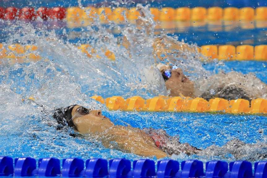 Two female swimmers participating in a backstroke race at the 2016 Olympics.