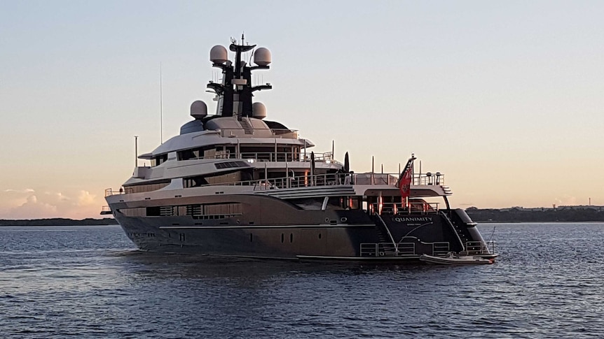 Rear angle view of the Equanimity super yacht on a calm sea at twilight with land in the distance