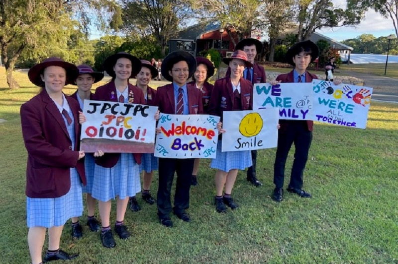A group of high school students holding signs.