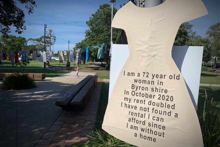 cut out of dress with text talking about homelessness, other dresses hanging on a clothesline