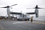 Military personnel board a helicopter on the deck of an aircraft carrier.