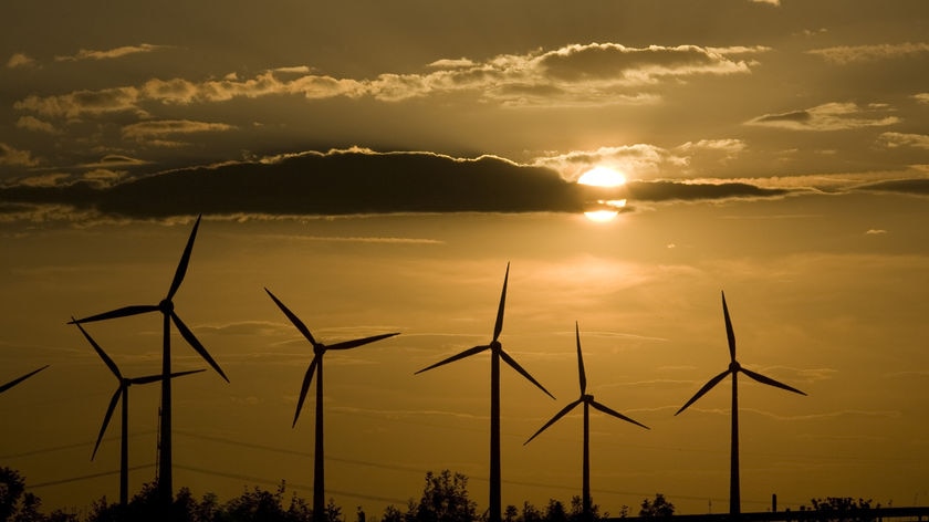 The sun sets behind power-generating windmill turbines