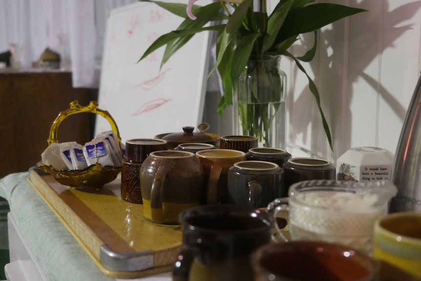 A tea station with upside down cups, tea bags and a jug of milk on display