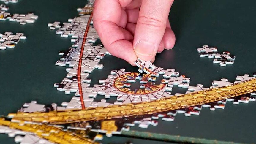 A man carefully places a puzzle piece.