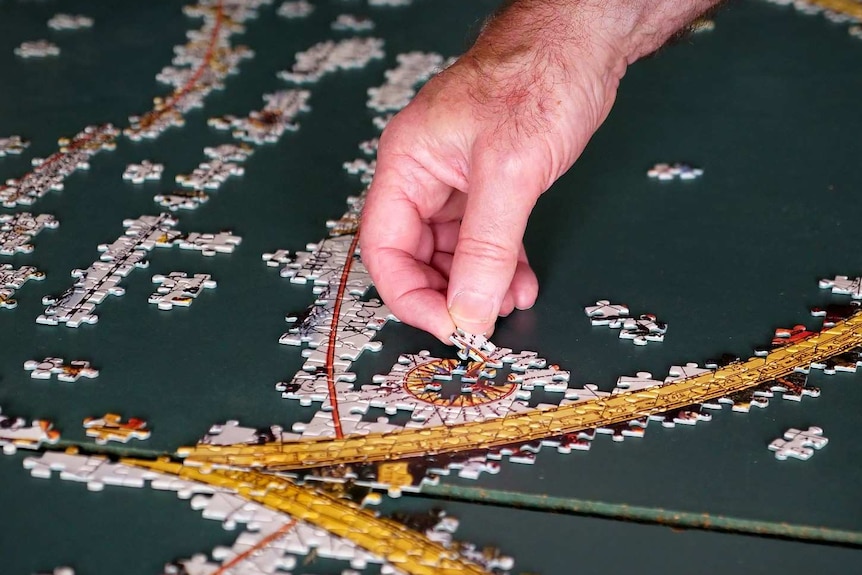 A man carefully places a puzzle piece.