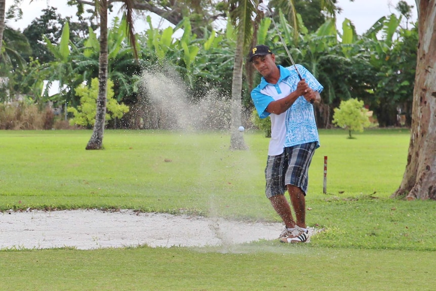 Sand sprays up as a golfer plays out of a bunker and onto the green.