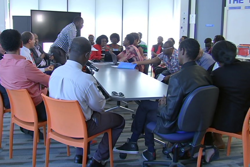 A group of African-Australian community leaders sits around a table.