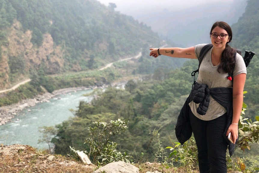 Australian traveller Amanda McDonald points to a dirt path and stream during a trek in Nepal mountains in 2018.