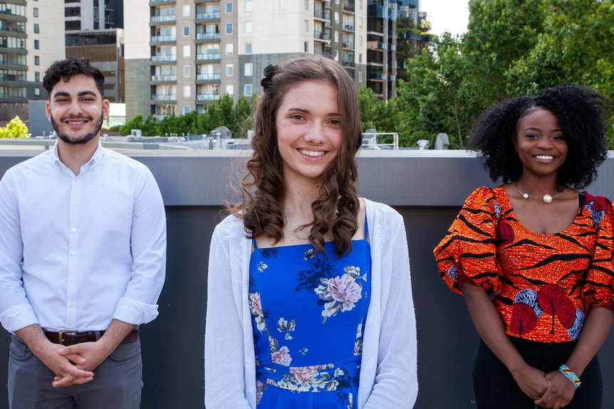Three young people standing side by side with the Melbourne skyline in the background.