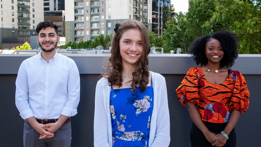 Three young people standing side by side with the Melbourne skyline in the background.