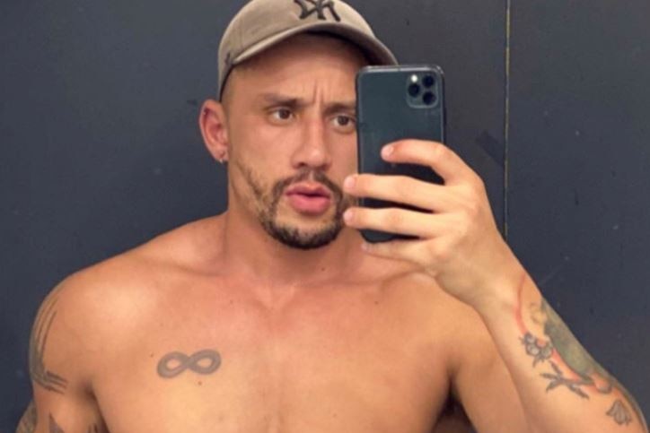 A shirtless man takes a selfie