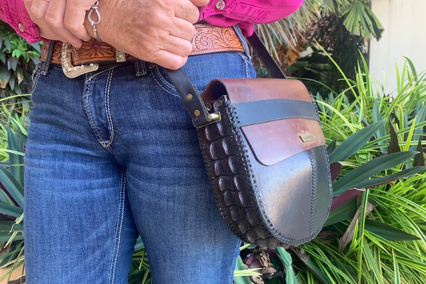 A close-up of a woman's simple crocodile skin handbag.