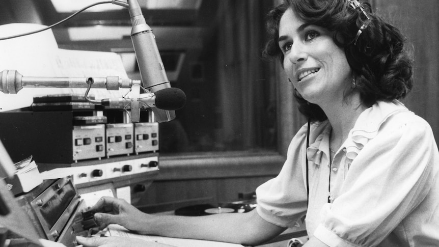 A black and white photograph of Mairi Nicolson wearing headphones and adjusting dials in the studio.